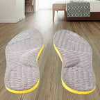 Par de palmilhas ortopédicas suporte de arco X cinza, para pés chatos, planos, pisada pronada, posicionadas sobre piso laminado, destacando o design ergonômico para conforto em todas as atividades diárias Universo Vigor Saúde