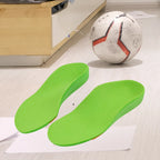 Par de palmilhas ortopédicas X infantis 3d, para pés chatos, planos, pisada pronada, verdes ambientadas no chão de um quarto ao lado de uma bola de futebol Universo Vigor Saúde