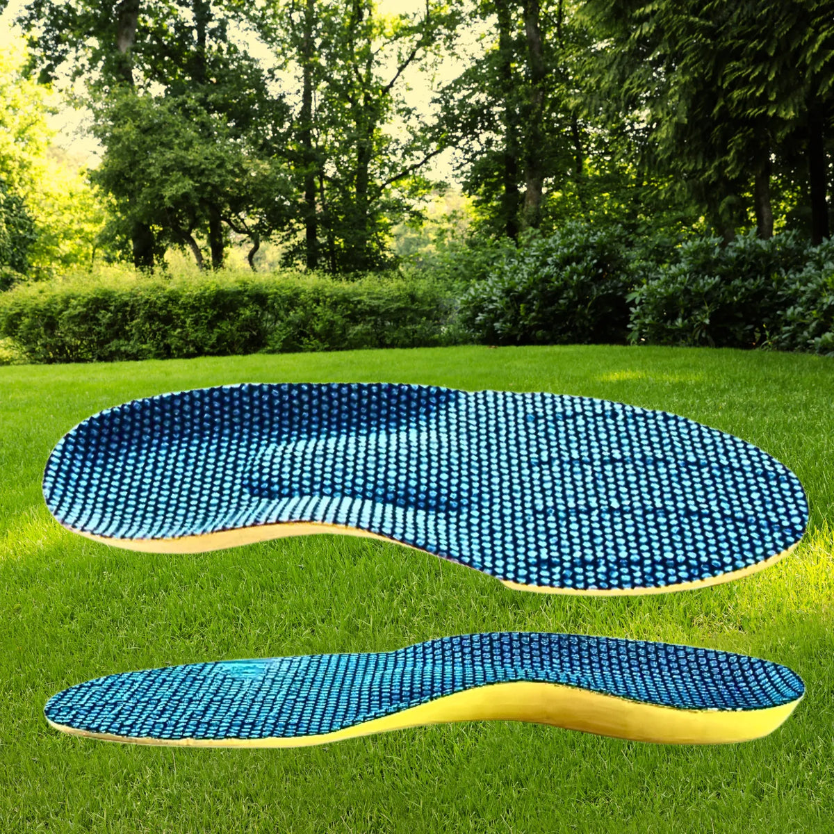 Par de palmilhas ortopédicas X anatômicas, para pés chatos, planos, pisada pronada, cor amarela disposto horizontalmente sobre gramado verde de parque com árvores ao fundo, destacando a face superior revestida em tecido azul com relevo ergonômico