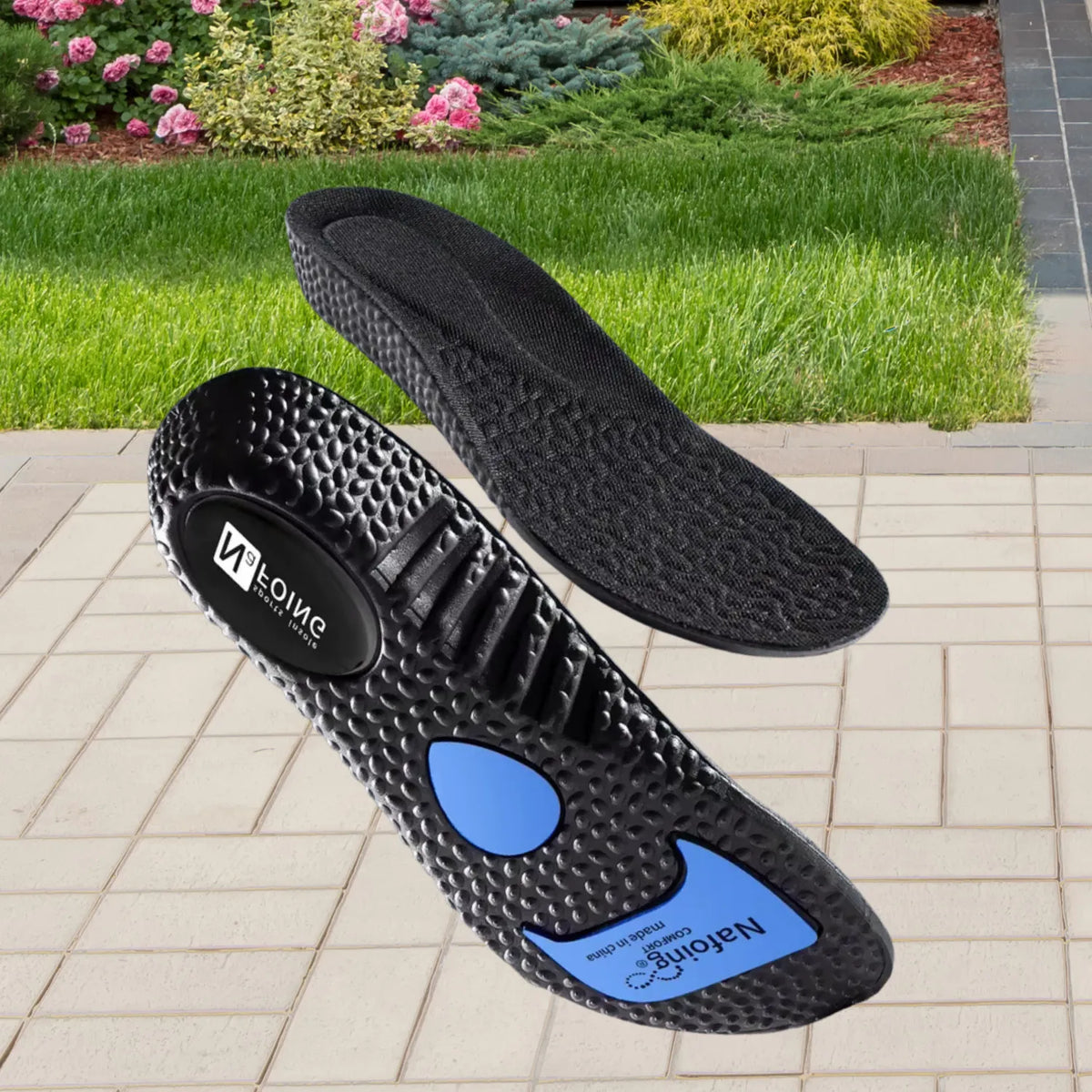 Par de palmilhas ortopédicas X esportivas pretas, para pés chatos, planos, pisada pronada, com detalhes azuis e textura antiderrapante em ambiente externo com jardim ao fundo Universo Vigor Saúde