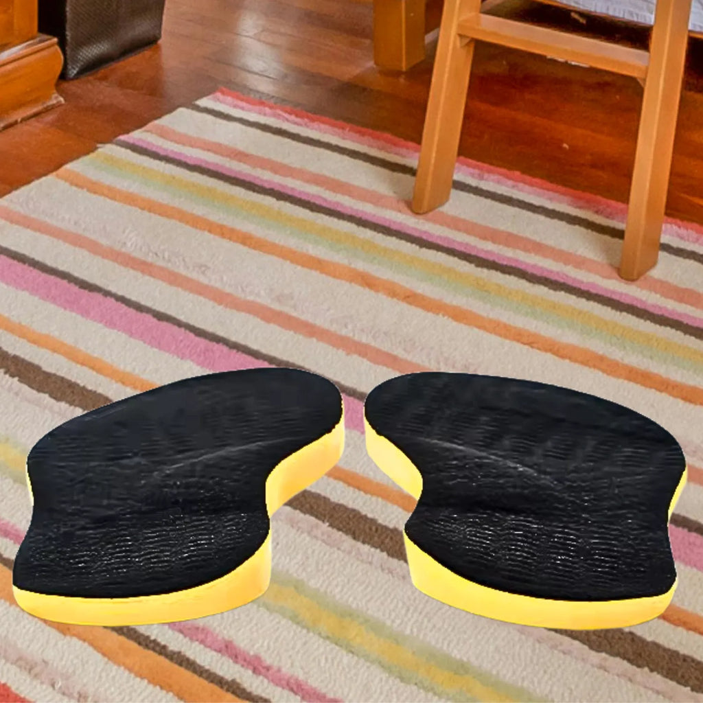 Par de palmilhas ortopédicas X pretas, pés chatos, planos, pisada pronada, posicionadas em ambiente doméstico, destacando o design ergonômico para alívio de dores em casa Universo Vigor Saúde