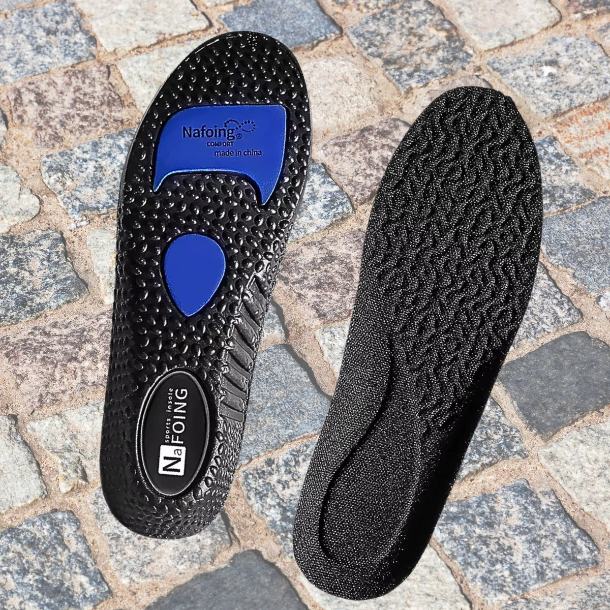 Apresentação dupla de palmilha ortopédica X na cor preta, para pés chatos, planos, pisada pronada, sobre fundo de pedras rústicas, exibindo o solado inferior texturizado com pontos de gel azul e a unidade direita com face superior em tecido escuro texturizado