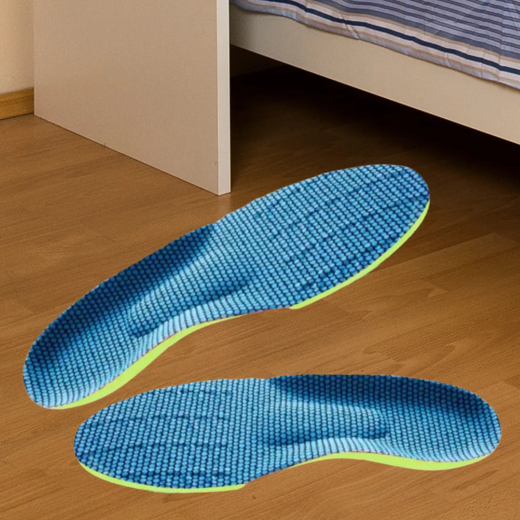 Par de palmilhas ortopédicas X anatômicas, para pés chatos, p-lanos, e pisada pronada, verde-limão disposto sobre piso de madeira laminada ao lado de uma cama, destacando a face superior em tecido azul texturizado e o relevo ergonômico de suporte