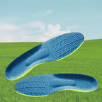 Par de palmilhas ortopédicas X ergonômicas, para pés chatos, planos, pisada pronada, na cor verde-limão com revestimento de malha azul texturizada, disposto sobreposto em um cenário de gramado verde e céu ensolarado ao fundo